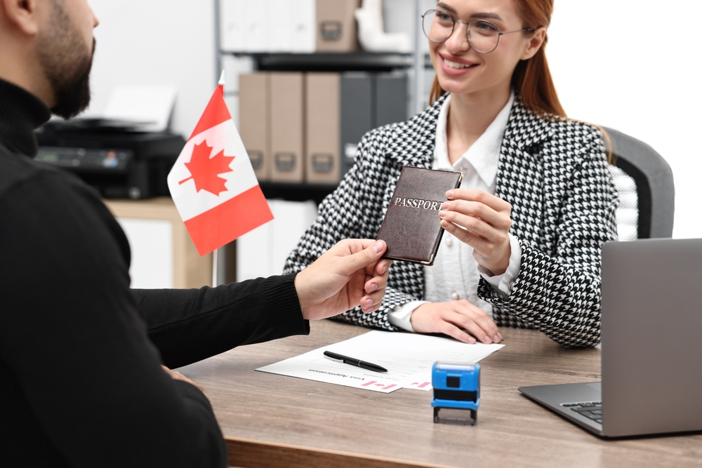 Provincial Nominee Program Canada: A picture showing an Embassy worker handing over passport to a successful PNP applicant.