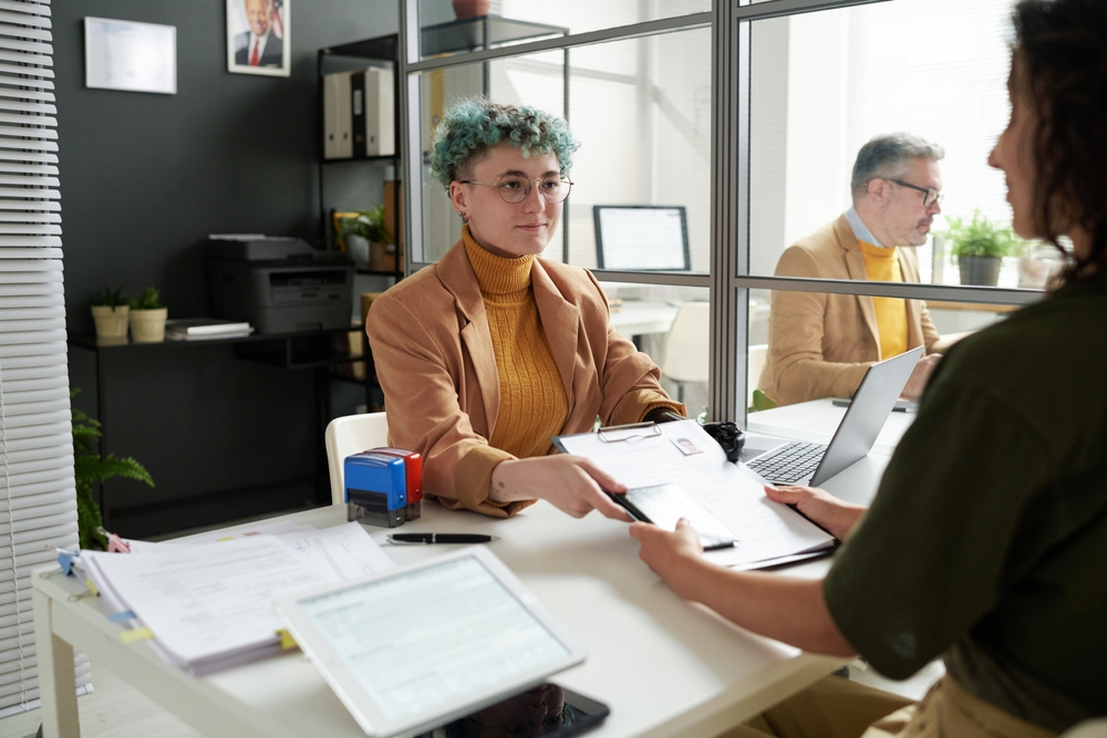 Canada Marriage Visa: A picture showing marriage visa applicant in an interview session, handing over documents to consular officer.