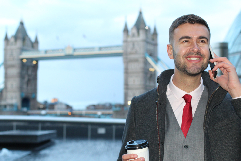 The 8 Worst Mistakes That Can Derail Your U K Employment Dreams: Picture of a young businessman calling by phone near Tower Bridge (London)