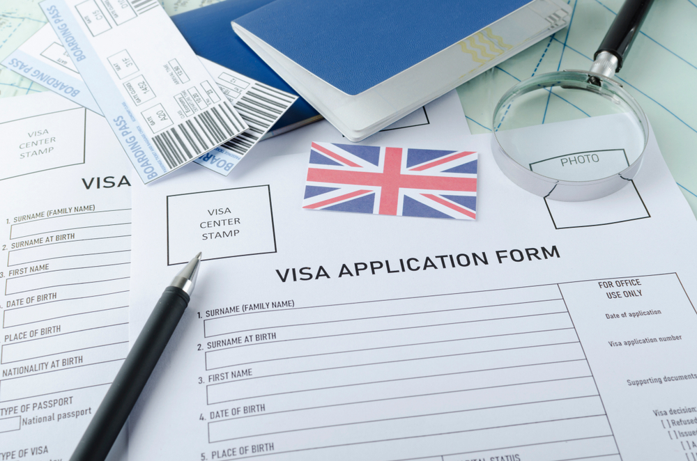 A No-Go List for UK Visa Hopefuls: Visa application form, passports, tickets, English flag, magnifying glass on the world map.